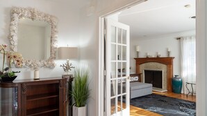 Una sala de estar con chimenea, un sofá y un espejo grande.