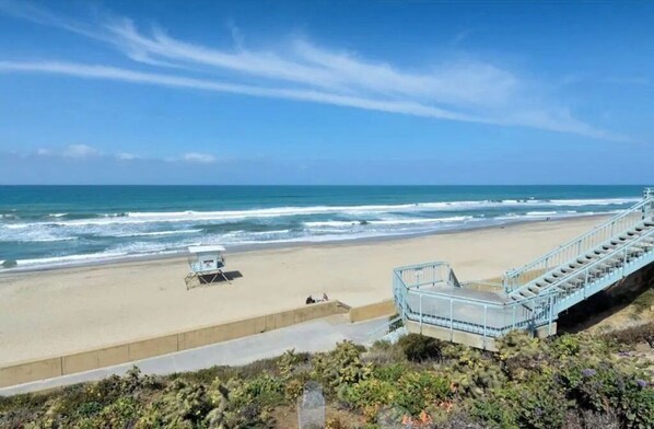 Walk along the beach to the lifeguard station, where the sandy shoreline stretches out to the clear sky.