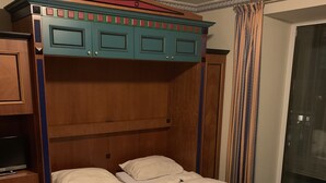 A double bed with a wooden frame and headboard, a small bedside table, and a television on the left. - Family apartment in the middle of Bad Gastein (Bad Gastein)