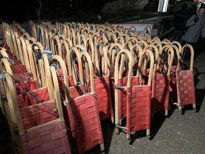Conjunto de cadeiras de madeira com almofadas vermelhas, dispostas em fileiras ao ar livre à noite.