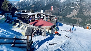 A ski resort with a wooden building, ski equipment, and a mountain backdrop. - Family apartment in the middle of Bad Gastein (Bad Gastein)