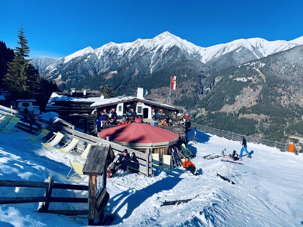 A ski resort with a wooden building, ski equipment, and a mountain backdrop.