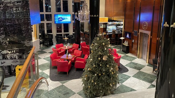 A lobby with a Christmas tree, red seating, a bar area, and a large screen displaying a menu. - Family apartment in the middle of Bad Gastein (Bad Gastein)