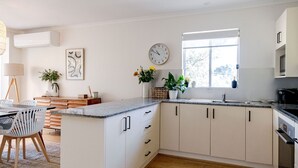 Een moderne keuken met witte kasten, een inbouwoven en een raam dat voor natuurlijk licht zorgt.