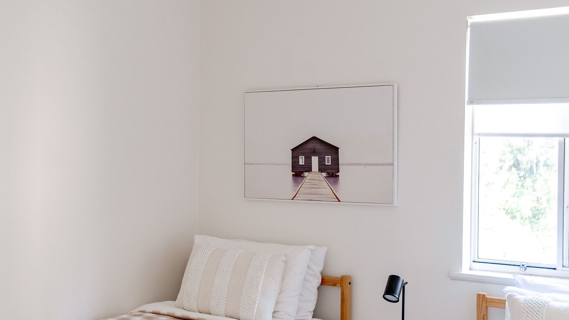 Une chambre à coucher avec un lit, une table de chevet, une lampe et une fenêtre.