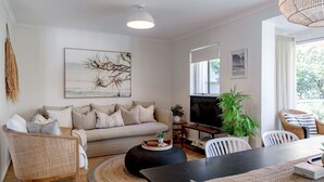 Een moderne woonkamer met een bank, stoelen, een eettafel en kunstwerken aan de muren.