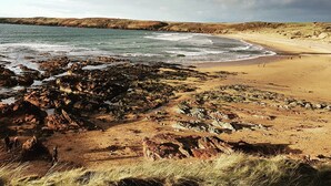 A coastal landscape with rocky terrain and a sandy beach.