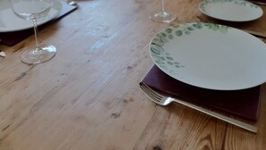 A dining table with plates and wine glasses, set against a white brick wall.