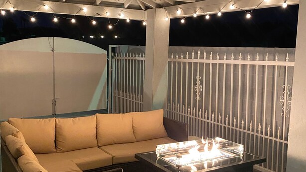An outdoor seating area with a sofa and ottomans, a fire feature, and string lights. - 1Bedroom guest suite NO CLEANING FEE w/free parking & WiFi for up to 4 guests (Las Vegas)