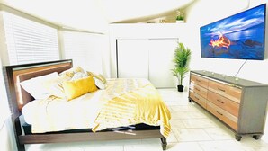A bedroom with a bed, a dresser, a television, and a potted plant. - 1Bedroom guest suite NO CLEANING FEE w/free parking & WiFi for up to 4 guests (Las Vegas)