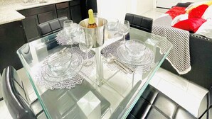 A modern kitchen with dark cabinets, a microwave, and a refrigerator. There is a dining table set with glassware and a bottle. The room has a white door and a red and white sofa. - 1Bedroom guest suite NO CLEANING FEE w/free parking & WiFi for up to 4 guests (Las Vegas)