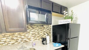A kitchen with dark cabinets, a stainless steel sink, a microwave, a black refrigerator, and a tiled backsplash. - 1Bedroom guest suite NO CLEANING FEE w/free parking & WiFi for up to 4 guests (Las Vegas)