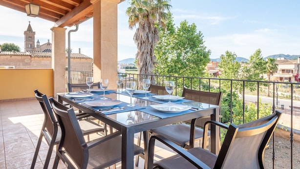 A terrace with a table set for dining, overlooking a cityscape with a church tower. - Ca'n Beato in Son Carrió (Son Carrió)