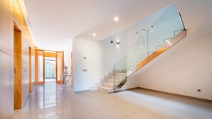 A modern interior with a glass staircase, wooden paneling, and a tiled floor. - Ca'n Beato in Son Carrió (Son Carrió)