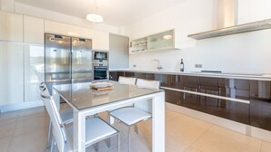 A modern kitchen with stainless steel appliances, a glass dining table, and a dark brown countertop. - Ca'n Beato in Son Carrió (Son Carrió)
