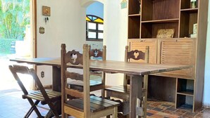 A dining area with a wooden table and chairs, a tiled floor, and a wooden cabinet with shelves. - Property with swimming pool, soccer field, Wi-Fi, and a lake with many fish. (Igaratá)