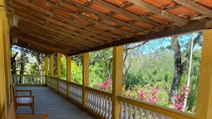 A covered outdoor seating area with benches, a tiled floor, and a view of lush greenery. - Property with swimming pool, soccer field, Wi-Fi, and a lake with many fish. (Igaratá)