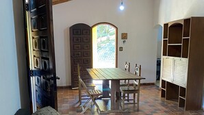A living room with a sofa, a dining table with chairs, a wooden ceiling, and a view through a window. - Property with swimming pool, soccer field, Wi-Fi, and a lake with many fish. (Igaratá)