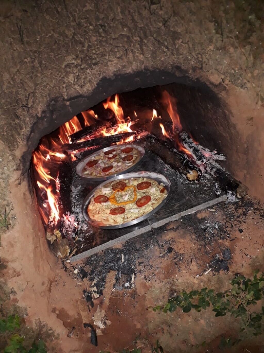 Deux pizzas cuisent dans un four à bois.