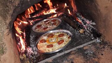 Deux pizzas cuisent dans un four à bois.