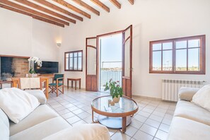Relax in this spacious living area with a high ceiling, featuring a comfortable sofa set, dining area, and brick fireplace.