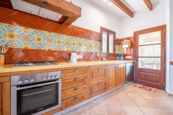 A kitchen with a Bosch oven, wooden cabinets, a tiled backsplash, and a wooden ceiling. - Ses Rotes de Son Rossinyol - Campos (Campos)