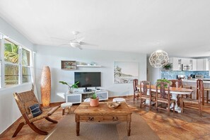 A spacious living area with a wooden coffee table, a TV, and a dining set. - Luxurious Penthouse Villa + Rooftop Terrace (Fajardo)