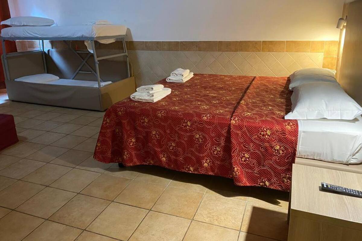 A hotel room with a bed, a bunk bed, and a small table with towels.