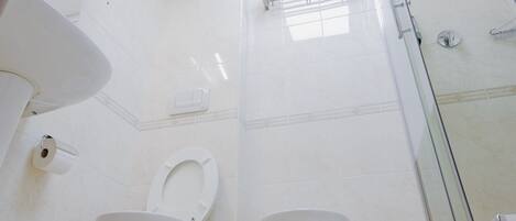 Une salle de bain moderne équipée de toilettes, d’un bidet et d’une douche à parois de verre.