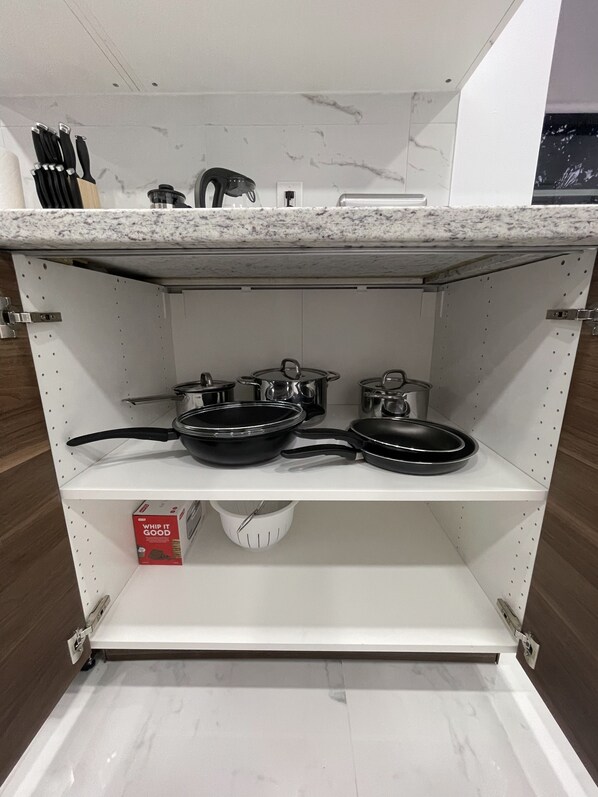 A kitchen shelf with cookware, a whisk, and a box labeled "WHIP IT GOOD".