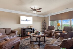 A living room with a fireplace, leather sofas, a coffee table, and a ceiling fan.