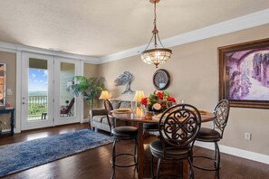A dining room with a round table, chairs, a chandelier, a clock, and a painting. - Luxury & Spacious Condo with Fantastic Lake Views Near Silver Dollar City w Free Tickets (Branson)