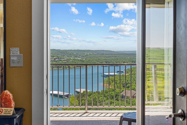 A view from a balcony overlooking a lake with a boat dock, surrounded by greenery and houses.