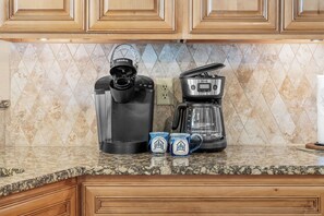 A kitchen with a coffee maker, a kettle, and two mugs on the counter.