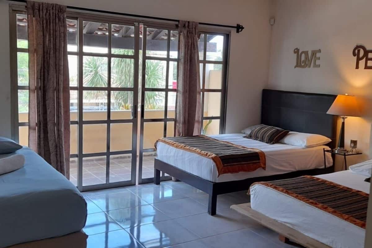 A hotel room with two beds, a large sliding glass door to the outside, and a wall with the word "LOVE" and "PEAR" partially visible.