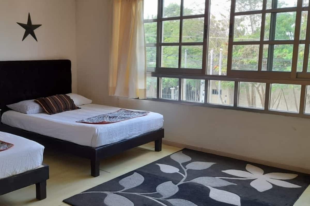 A bedroom with two beds, a window with a view, and a star decoration on the wall.