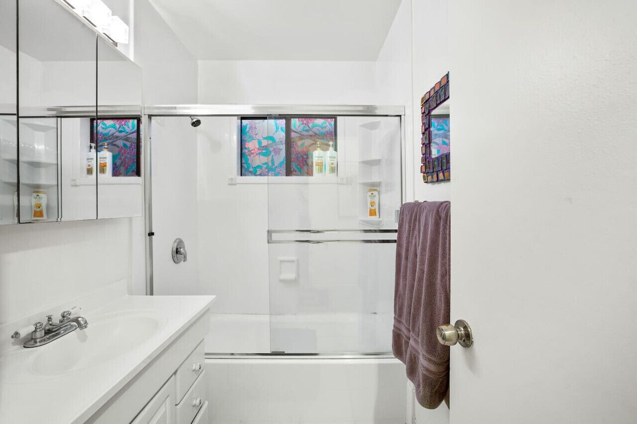 Ein modernes Badezimmer mit Duschkabine aus Glas, einem weißen Waschbecken und einem Spiegel.
