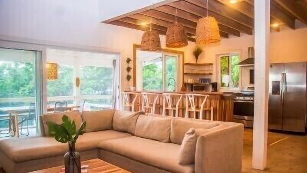 A modern living room with a sectional sofa, wooden coffee table, and hanging wicker lamps. - Sea Cloud, Private home with salt water pool / Sea views (West Bay)