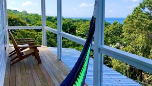 A hammock on a wooden deck with a view of the ocean and greenery. - Sea Cloud, Private home with salt water pool / Sea views (West Bay)