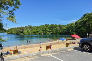 A beach with a wooden barrier, a parking area, and a lake.