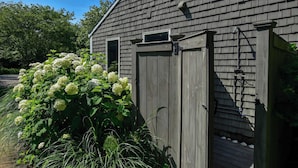 A wooden building with a garage door, a small window, and a water spigot.