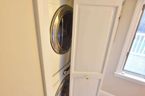 Ein Waschraum mit Waschmaschine, Trockner und einer Tür.