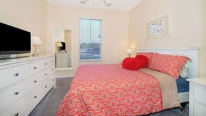 Un dormitorio con cama, cómoda, ventilador de techo, ventana y obra de arte en la pared.