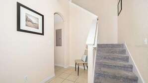 Una escalera con una pared color crema y un cuadro enmarcado a la izquierda.