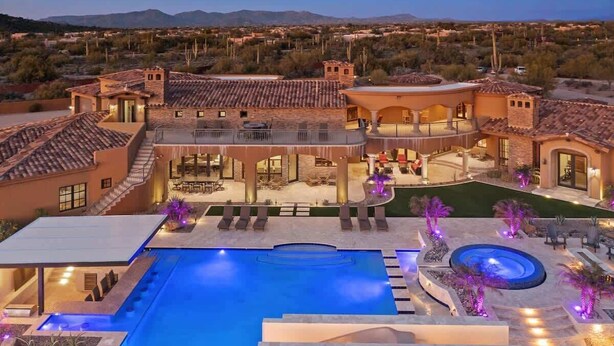 A large, luxurious house with a swimming pool, outdoor seating, and a hot tub.