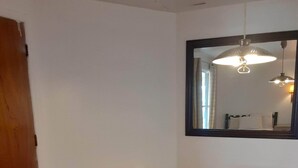 A room with a wooden floor, a small table, two red chairs, a wooden door, and a mirror on the wall. - 66 Motel (Holbrook)