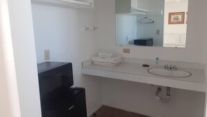 A small, clean bathroom with a white sink, a mirror, a towel rack, and a black appliance, possibly a microwave. - 66 Motel (Holbrook)