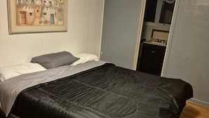 A bedroom with a bed, a painting on the wall, and a door leading to a bathroom. - 66 Motel (Holbrook)