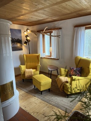 Une pièce chaleureuse avec des fauteuils jaunes, une petite table ronde et une grande fenêtre avec des rideaux.