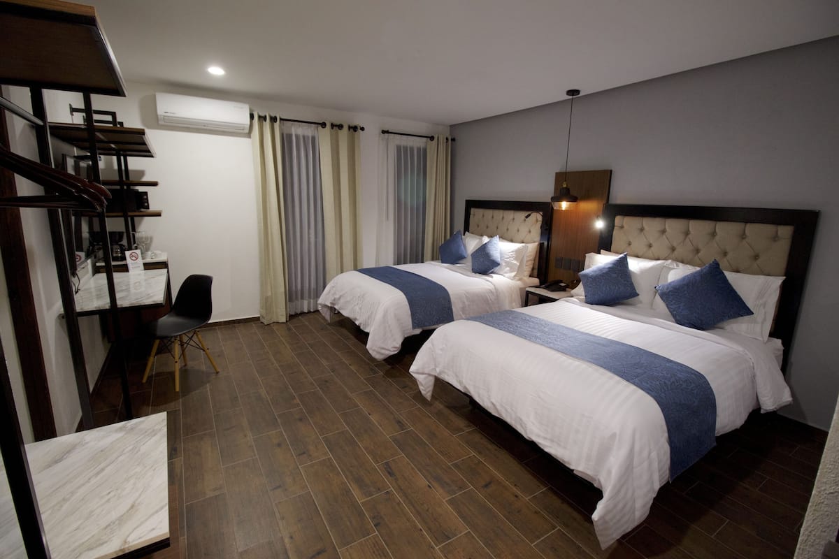 Une chambre d’hôtel avec deux lits, un bureau et une chaise.